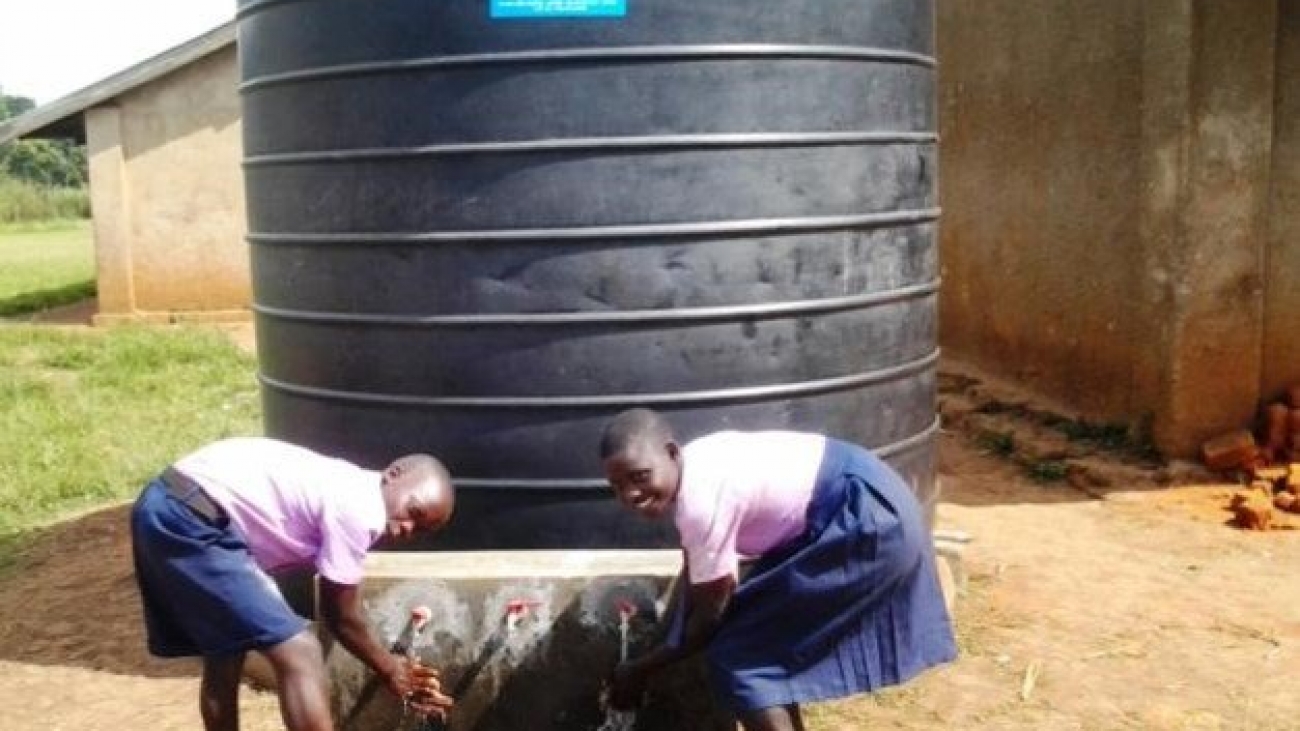 Students at Karongo Primary school washing their hands at the newly installed water tank at their school