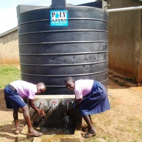 Students at Karongo Primary school washing their hands at the newly installed water tank at their school